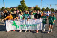Children posing in front of a banner at an event.