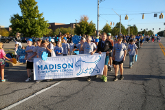 People in a group holding a sign that says "Madison elementary school" at an event.