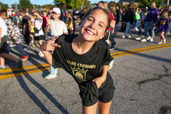 Girl in black shirt smiling at camera at parade.