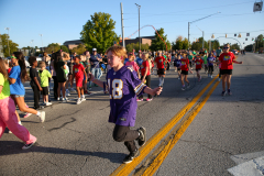 People running in a parade on a street.