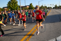 People running in a parade on a road.