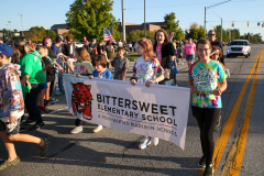 People gathered around a sign at a parade.
