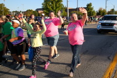People walking in a parade, waving to onlookers.