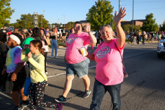 People at a parade waving to crowd.