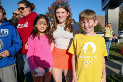 Three children standing in front of a building at an event, posing for a picture.