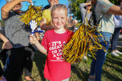 Girl in red shirt holding cheerleading pom poms.