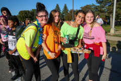 Four young women posing together at a parade, smiling and holding food items.
