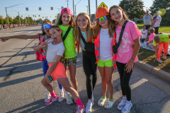 Girls in colorful costumes posing for a picture at a parade.