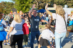 Man in a black t-shirt giving high fives to people at a parade.