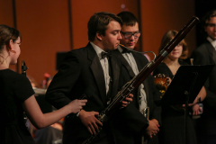 Musicians performing on stage with a conductor leading them.