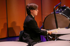 Young musician playing drums on stage.