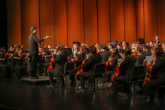 Conductor leading an orchestra on stage.