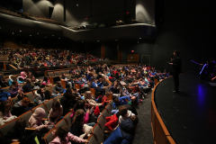 Auditorium filled with people watching a performance on stage.