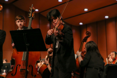 Man playing violin on stage during concert.