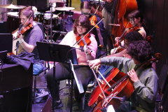 Musicians performing on stage in front of an audience.