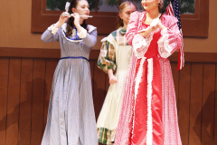 Two women in historical costumes performing on stage.
