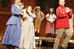 Group of people on stage performing in a musical production.