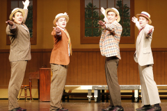 Five men on stage dressed as characters from the musical "The Music Man". They are pointing in different directions and