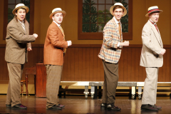 Five men on stage dressed in suits and ties, posing for a picture.