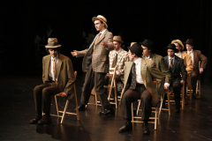 Theatrical performance of a group of men in costumes on stage.