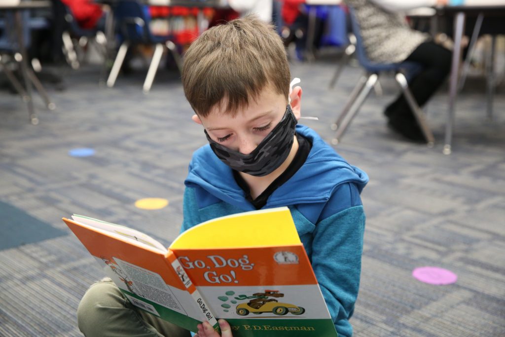 Child Reading Book on Floor
