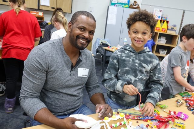 father and son in classroom making gingerbread house