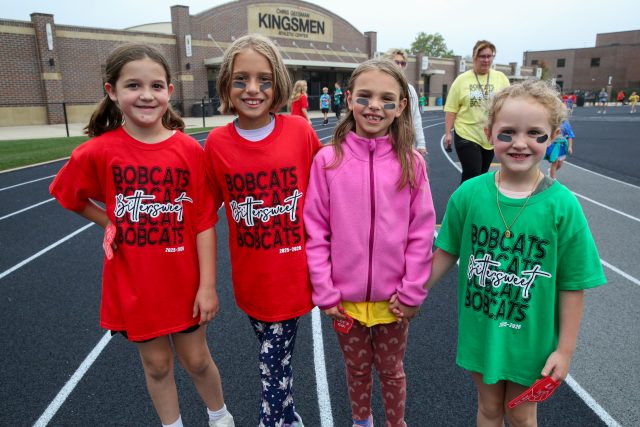 students wearing Bobcats shirts in front of Kingsmen building