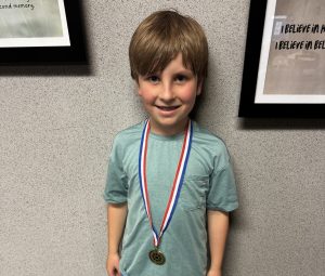 Young boy wearing a medal around his neck.