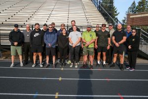 This is a group of people standing together in front of an athletic field.