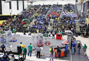 Large indoor sports arena filled with people watching a robotics competition.