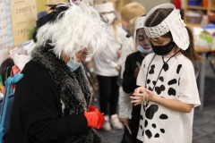 Teacher dressed as a witch, interacting with students in a classroom setting, possibly during an educational activity like