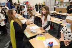 Children in a classroom participating in a pumpkin catapult activity.