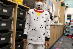 Young boy in dalmatian costume standing in classroom.