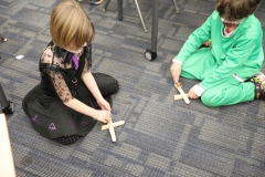 Two children playing with a pumpkin catapult in a classroom setting.