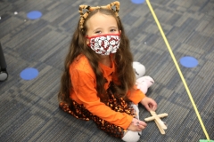 Child in costume sitting on floor looking at camera.