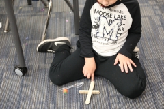 Child sitting on floor playing with toy blocks in front of classroom desk.