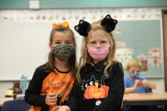 Two children wearing masks in a classroom setting.