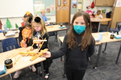 Girl in a black shirt holding up a pumpkin catapult.