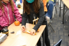 Two children building pumpkin catapults at school.