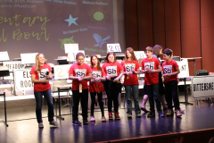 Students on stage participating in a spelling bee competition.
