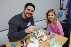 Man and child decorating gingerbread house together.