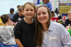 Woman and child posing in front of classroom setting.