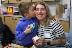 Woman hugging child in classroom setting.
