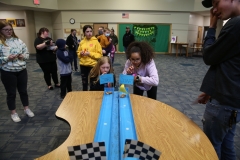 Children playing with a toy car on a table in a room.