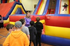 Group of children gathered around inflatable bounce house.