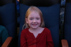 Young girl sitting in movie theater seat.