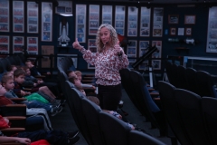 Woman giving thumbs up in front of audience, possibly at a movie screening or presentation.