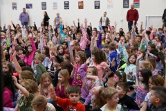Children in a classroom raising their hands.