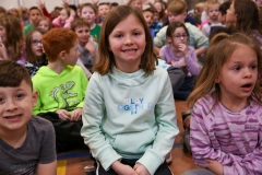 Girl sitting on floor in front of group of children.