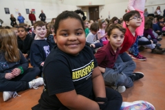 Young girl sitting on floor in front of group of children.